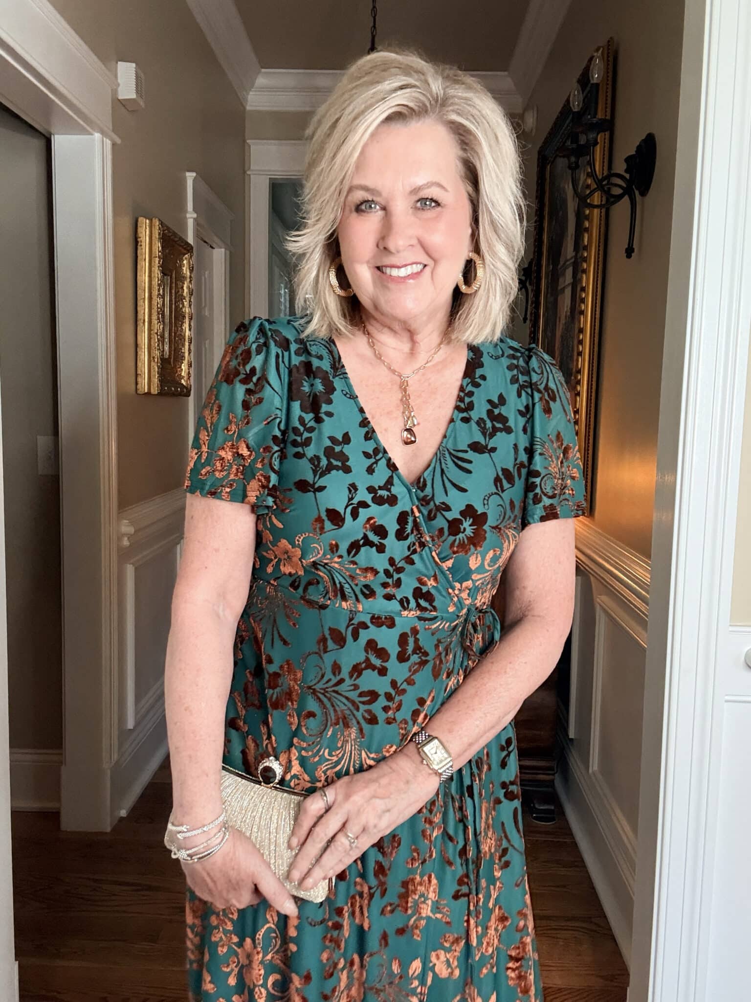 Tania wearing an Amazon green and rust velvet dress with a gold clutch