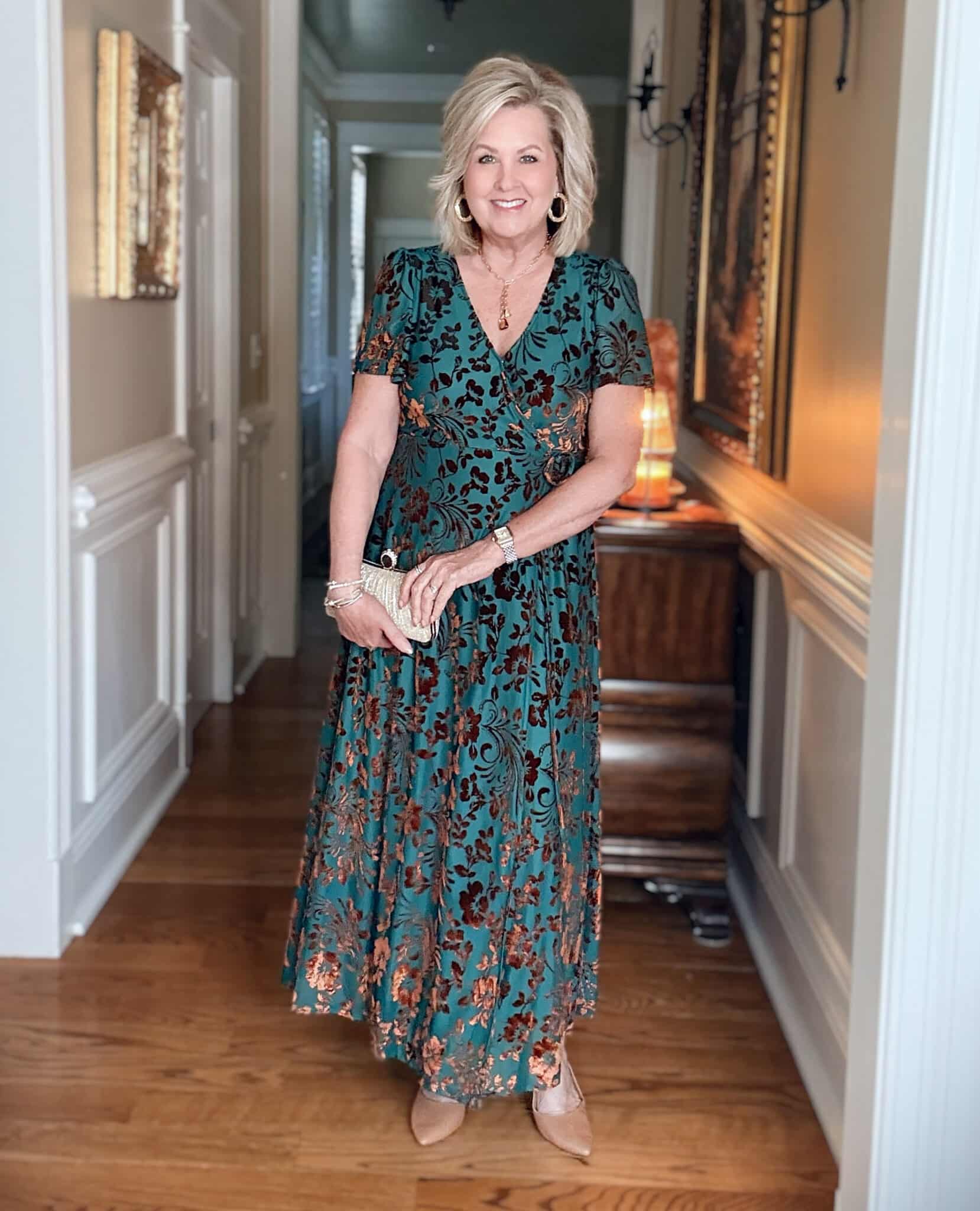 Tania wearing an Amazon green and rust velvet wrap dress with a clutch