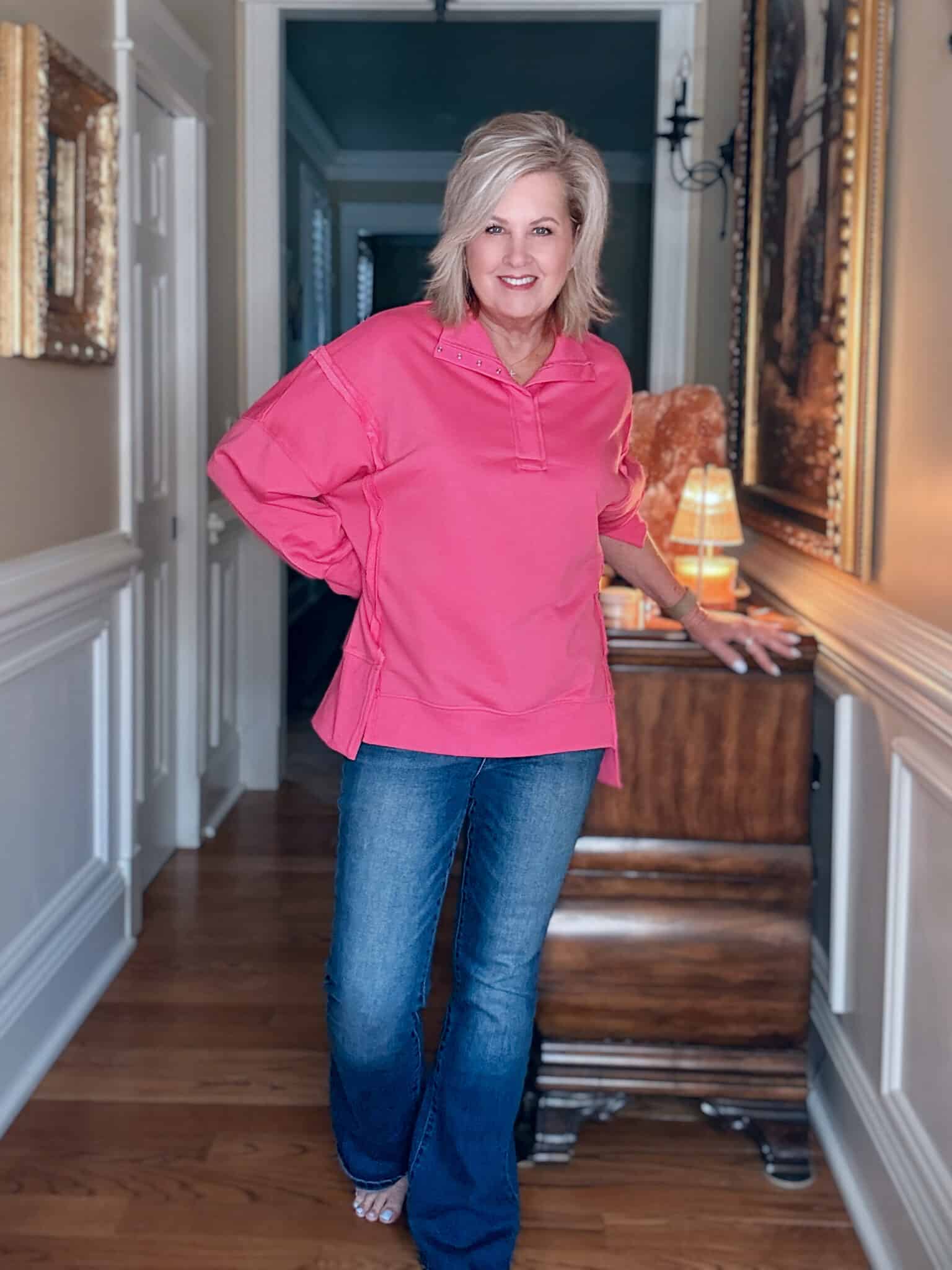 Tania wearing a bright pink oversized sweatshirt with dark wash flare jeans