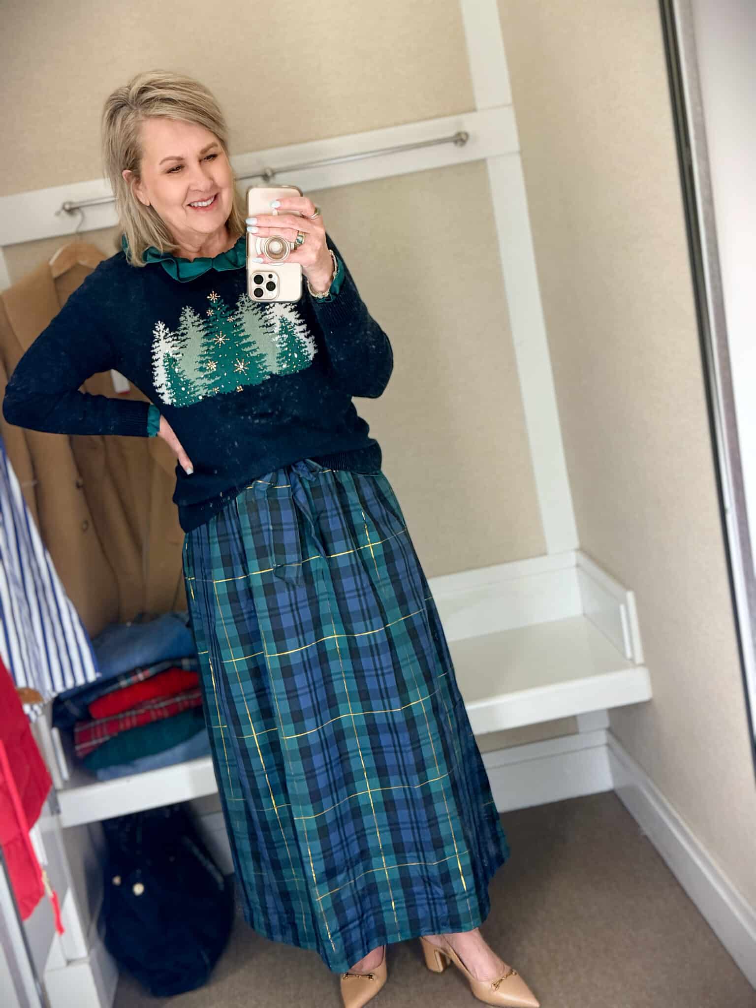 Tania trying on a navy sweater with green Christmas trees with a blue and green taffeta skirt from Talbots