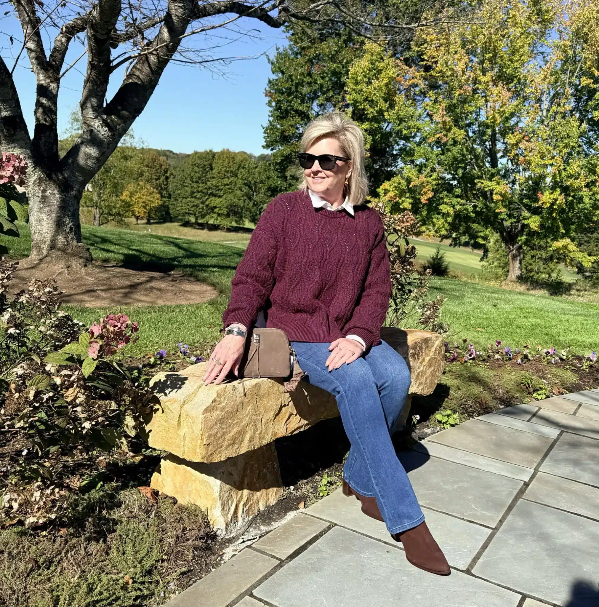 Tania wearing a burgundy cable-knit sweater with jeans and brown boots, a cozy casual Thanksgiving outfit.