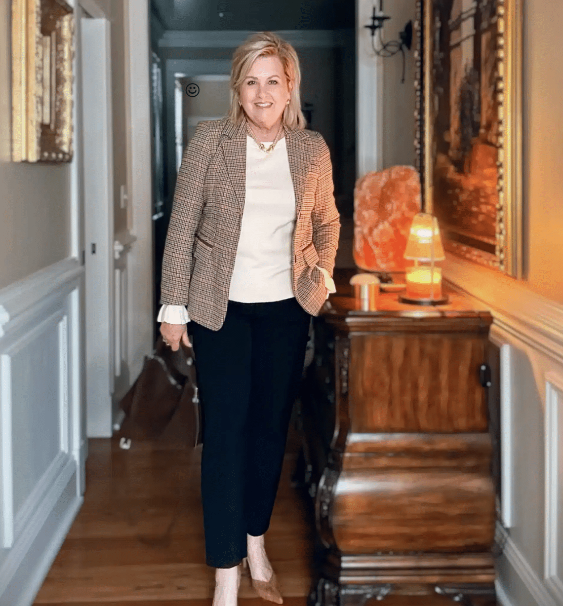 Tania wearing a plaid blazer over a cream sweater with black pants and brown heels, a polished Thanksgiving outfit idea.