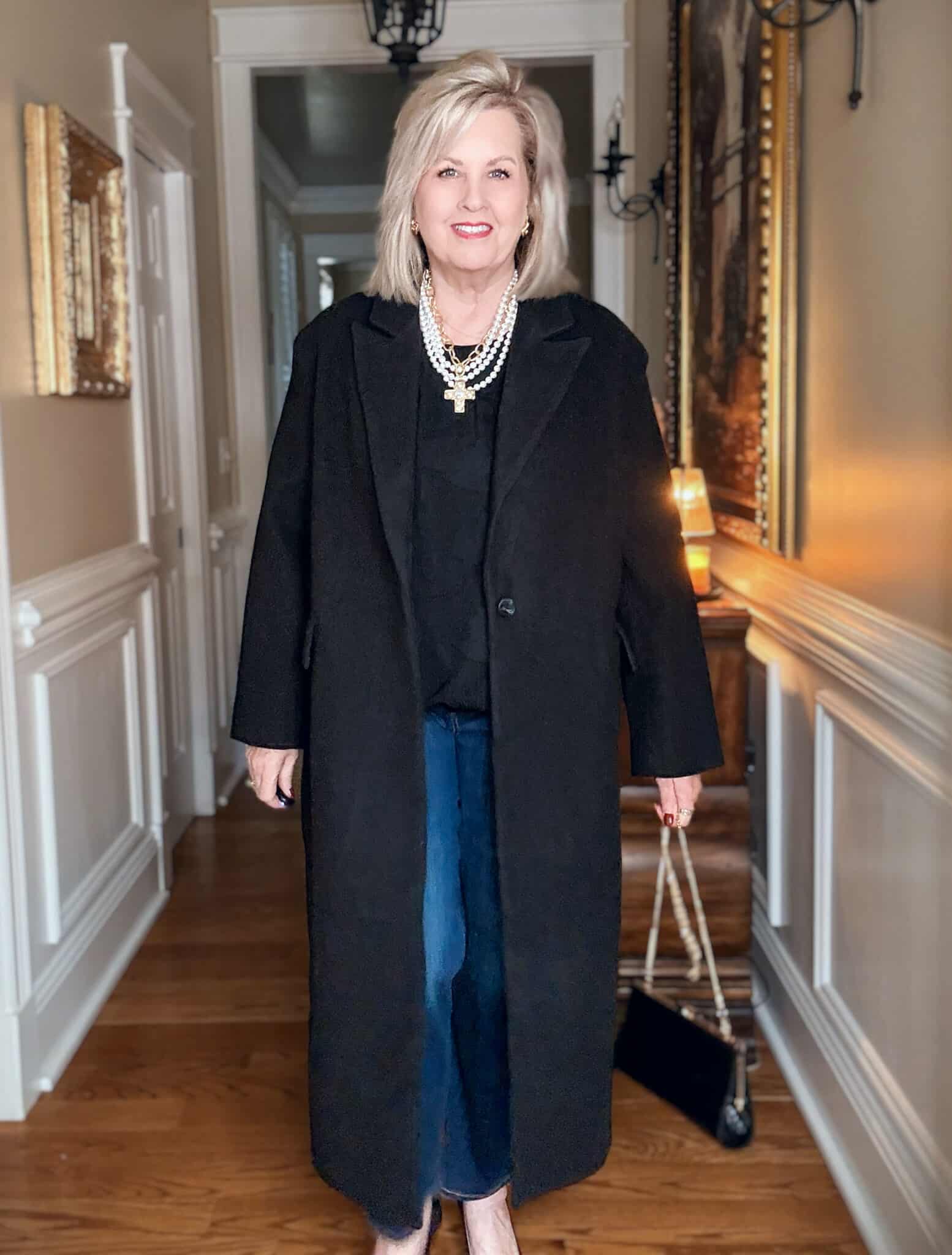 Tania wearing a black dress coat from Walmart with a black top and pearl necklace