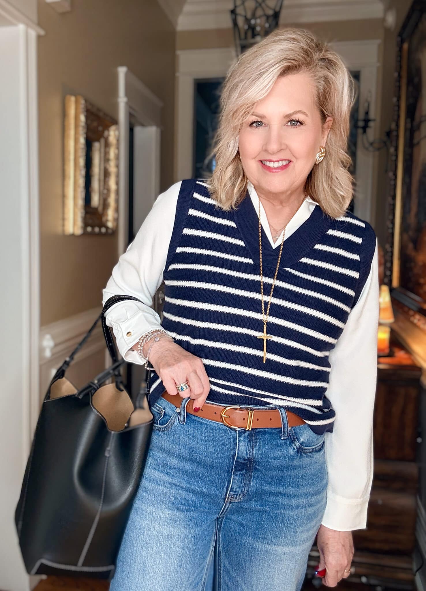 Tania wearing a sweater vest/white shirt combo with a brown leather belt from Quince