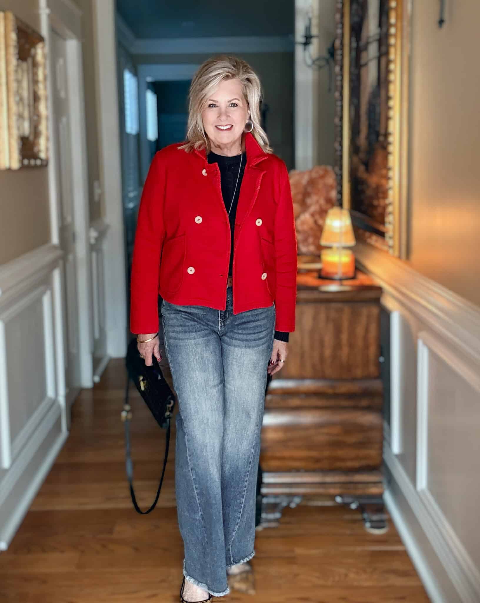 Tania wearing a navy cableknit sweater with frayed jeans and a red double breasted jacket