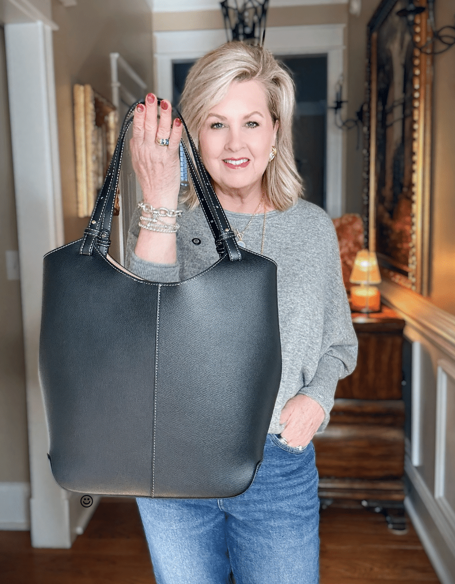 Tania wearing a gray Sweater and holding a black leather handbag from Quince with Talbots jeans