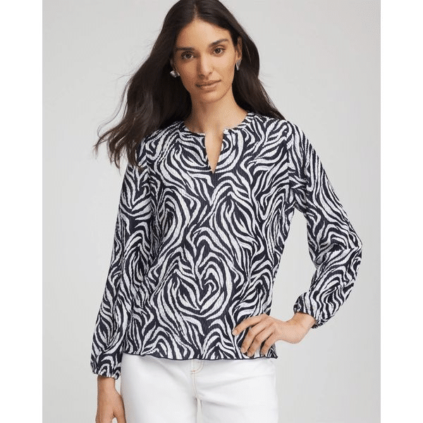 Woman wearing a navy and white zebra print blouse with white jeans.