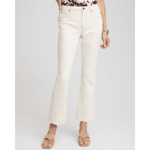 Woman wearing white cropped kick flare jeans with nude sandals and a printed top.