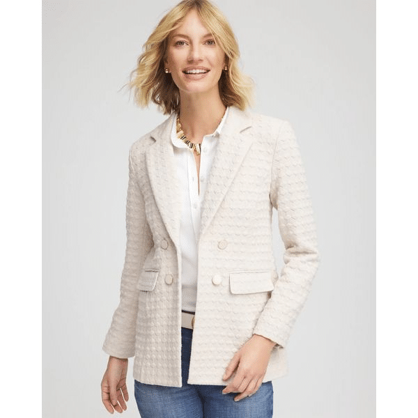 Woman wearing a cream textured blazer over a white blouse and jeans.