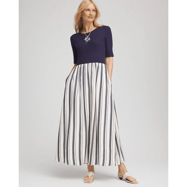 Woman wearing a navy short-sleeve top and a flowing navy and white striped maxi skirt dress, styled with sandals.