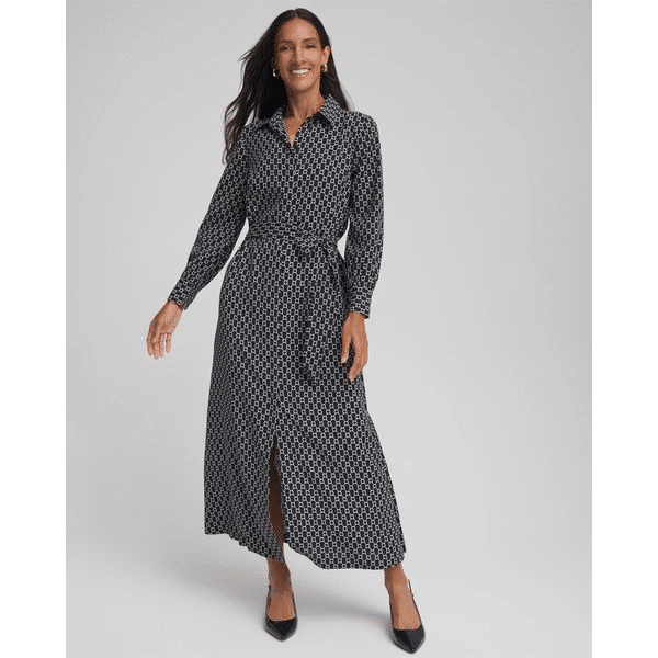 Woman wearing a long-sleeve shirtdress with a small geometric print, belted waist, and front slit, styled with black heels.