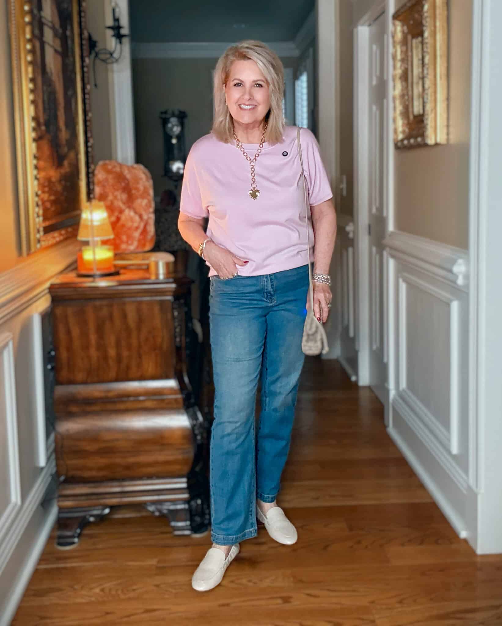 Woman wearing a light pink sweater with jeans and layered jewelry