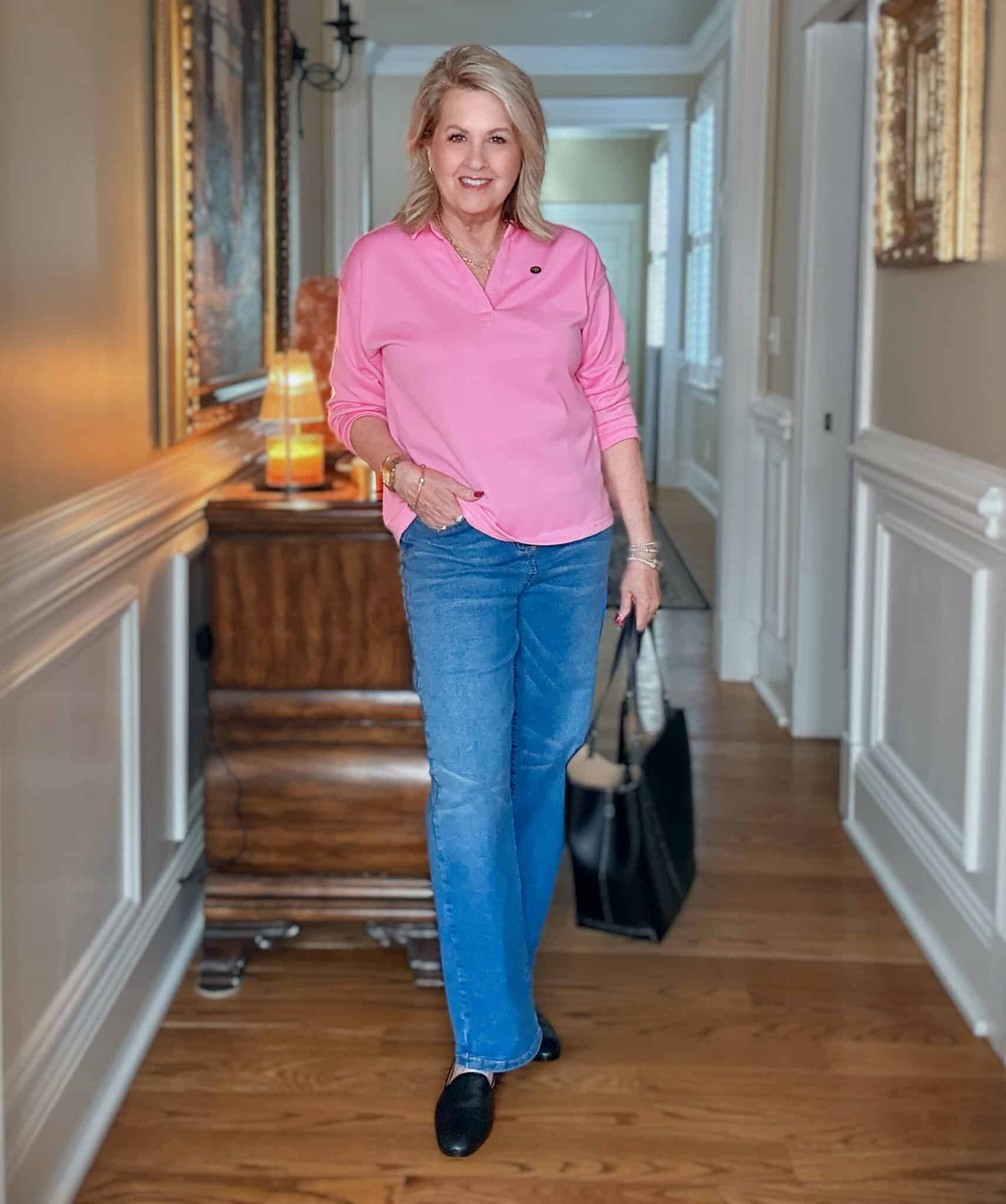 Tania wearing a bright pink polo style top, jeans, and a black tote