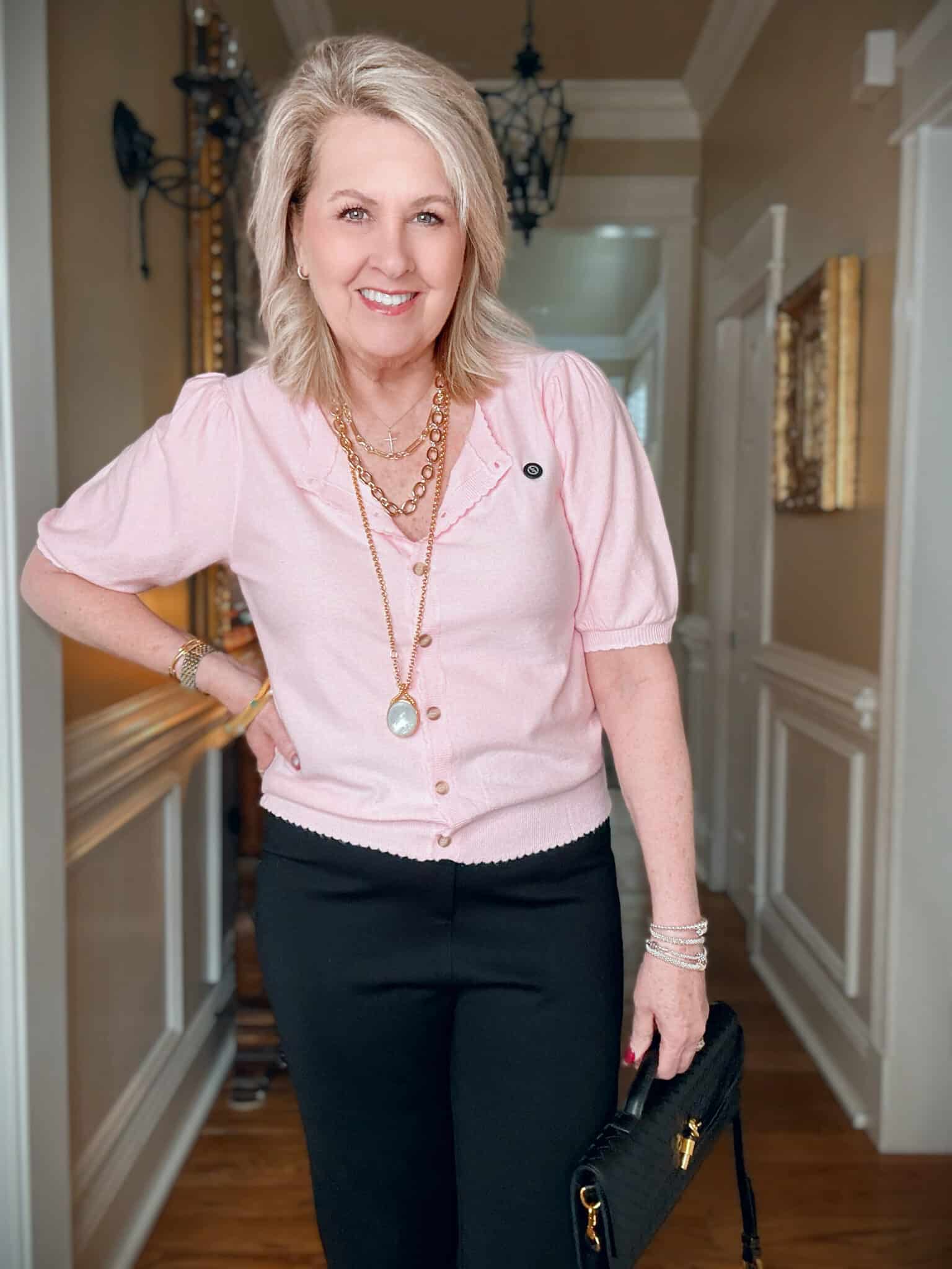 Woman wearing a pink puff sleeve cardigan with multiple necklaces