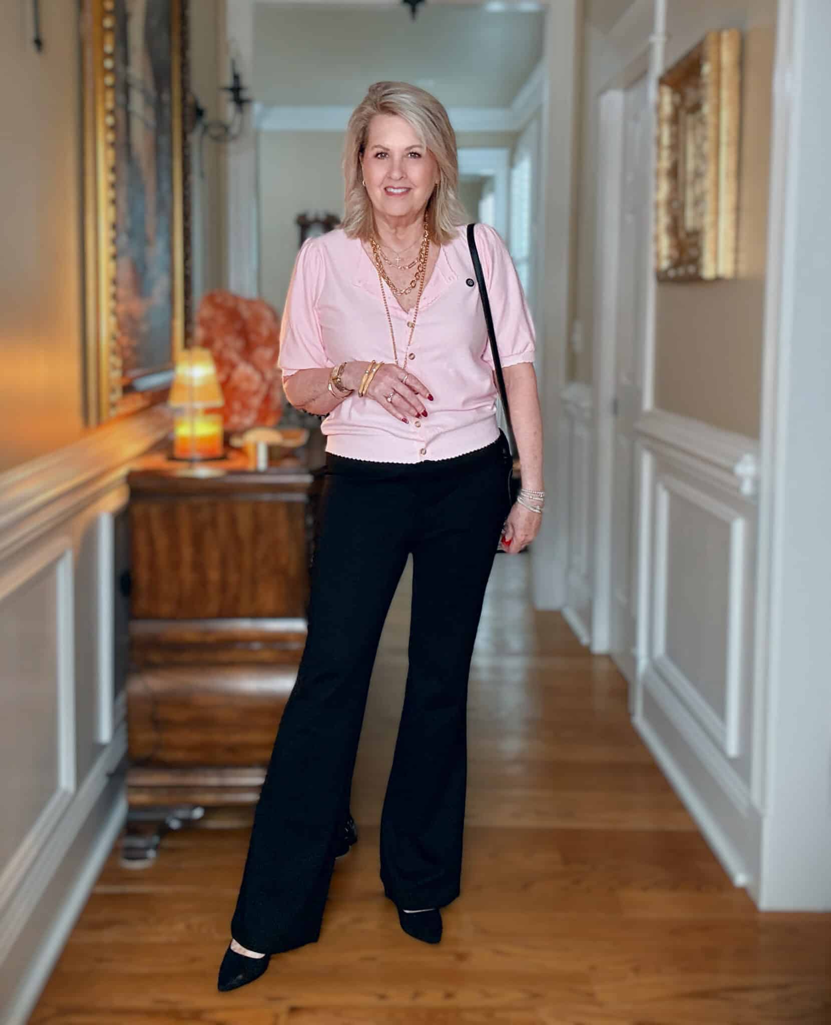 Woman wearing black dress pants with a pink puff sleeves cardigan