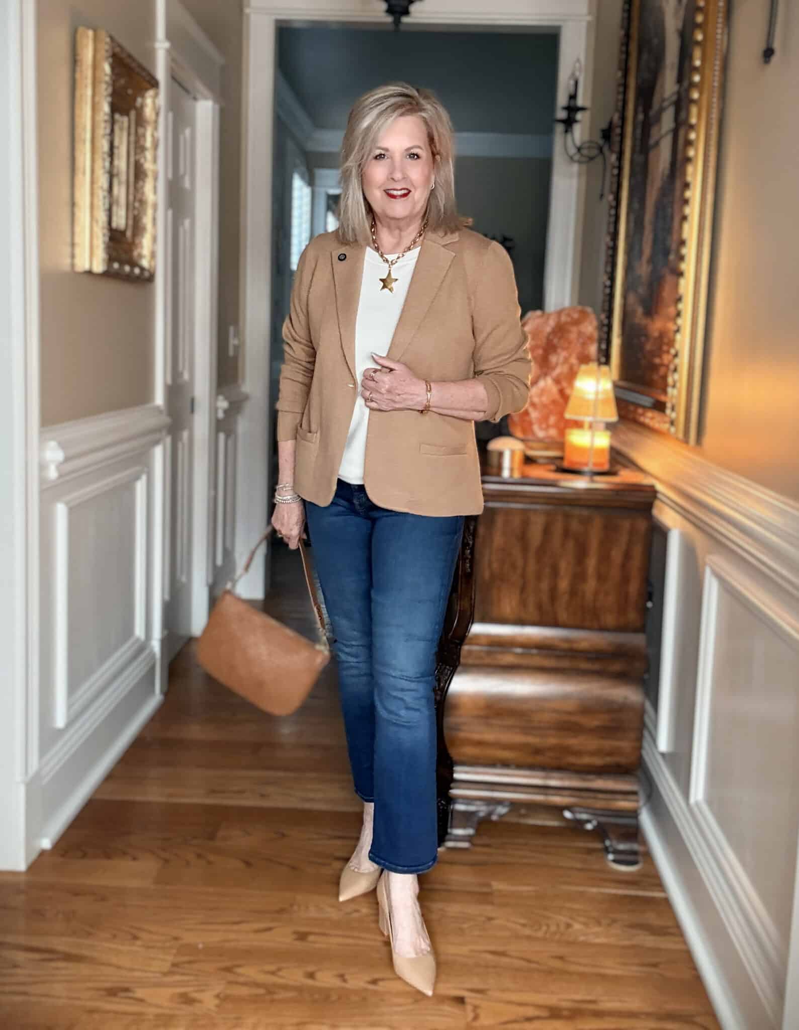 Tania wearing a tan sweater blazer with a white shirt and straight cropped frayed jeans