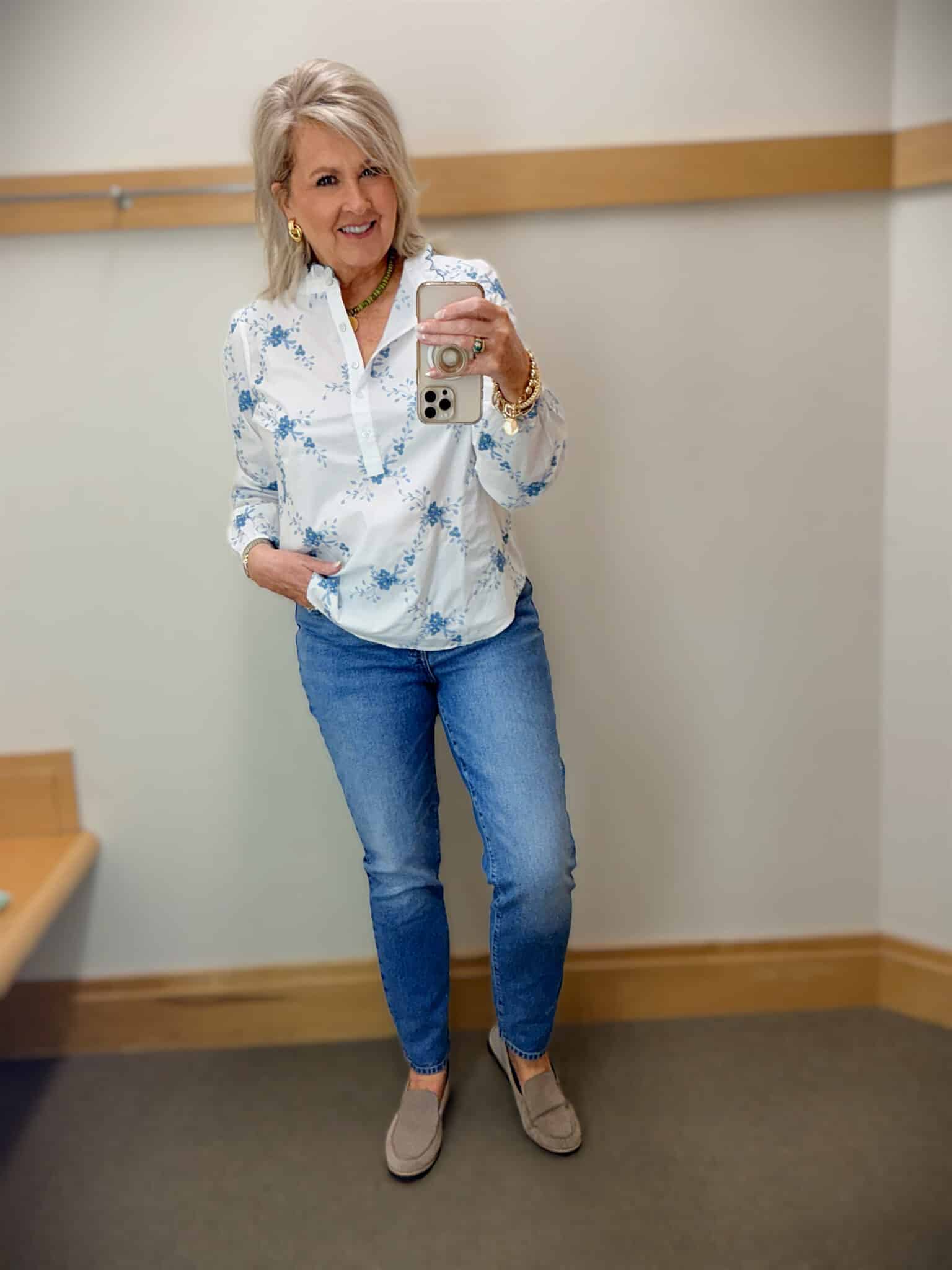 woman over 50 wearing blue embroidered floral ruffle top with slim ankle jeans