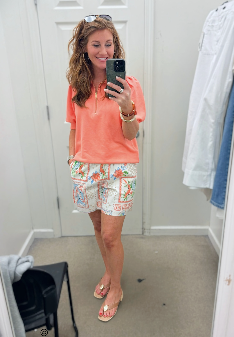Stephanie styling a bright orange top and printed shorts for petites from Belk